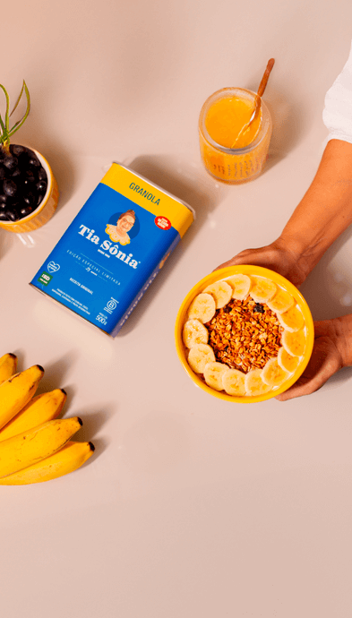 Foto com mesa de frutas, suco e tigela de açaí com Granola Tradicional Tia Sônia