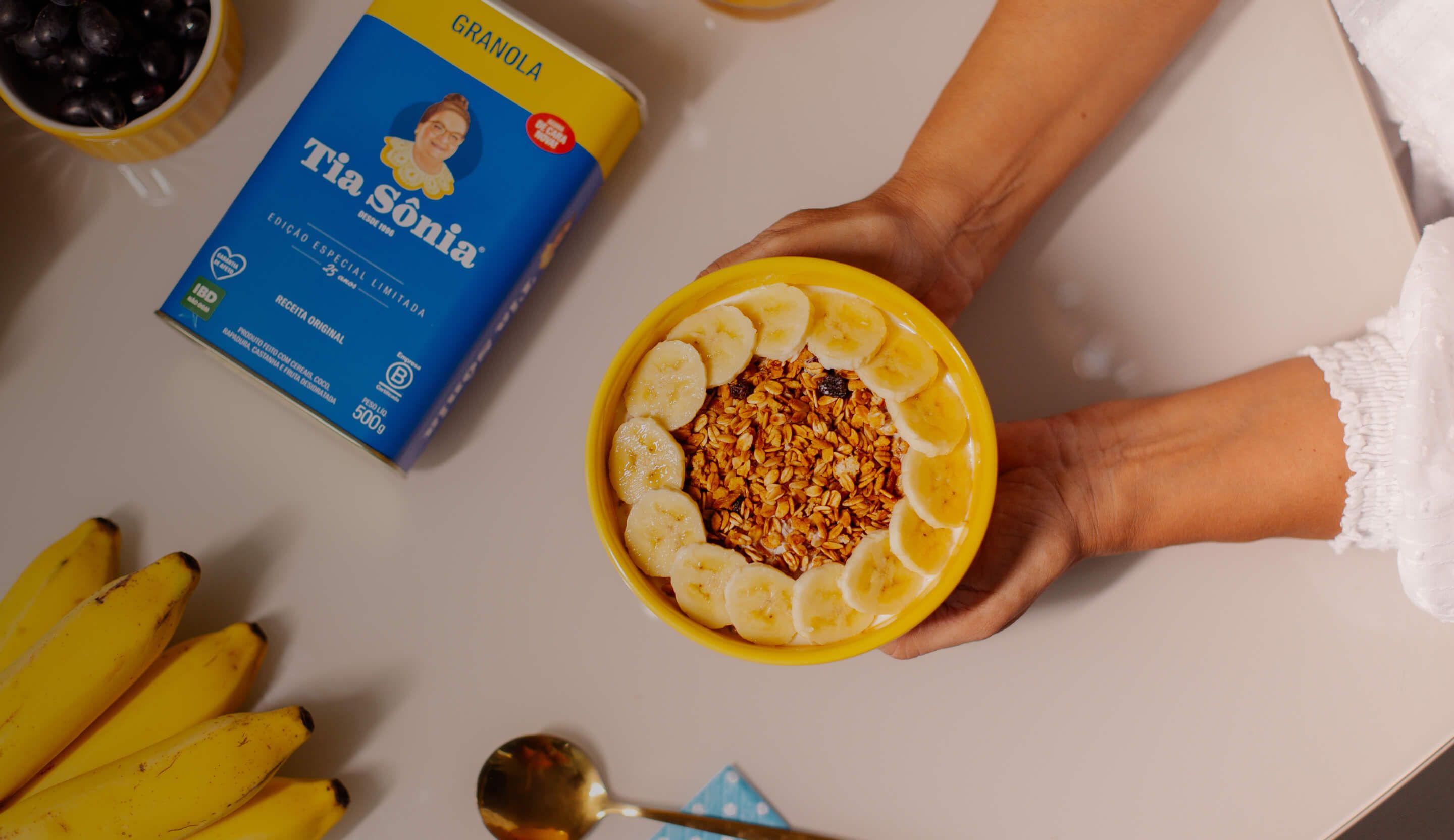 Foto com mesa de frutas, suco e tigela de açaí com Granola Tradicional Tia Sônia