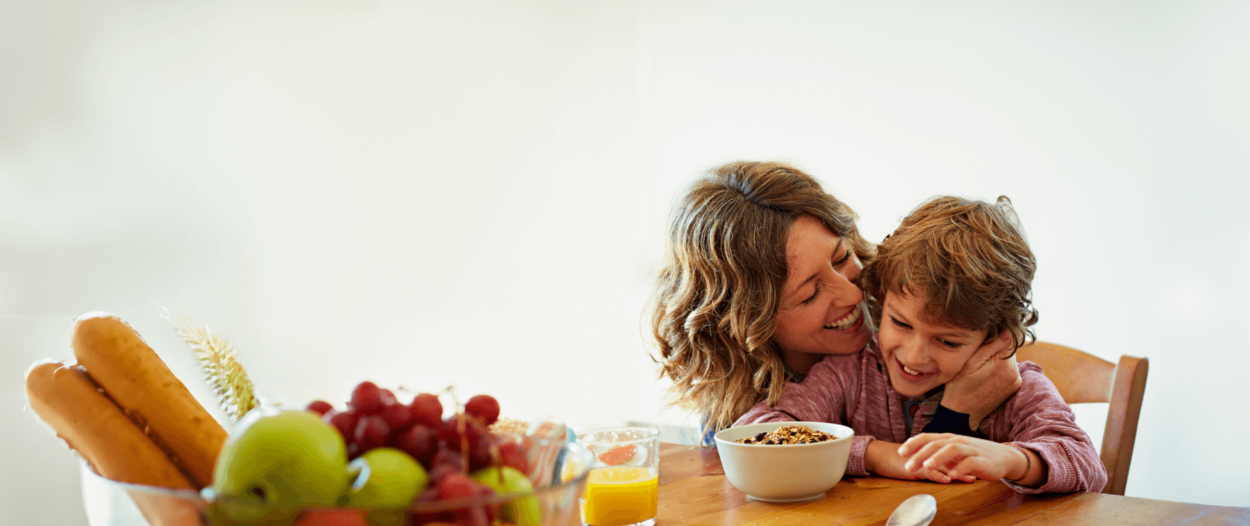 Foto de mãe e filho amorosos em mesa farta de granola e frutas